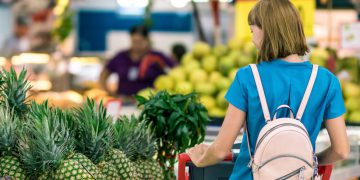 a woman taking a look through some pineapples in a supermarket